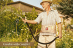 Man watering plants in a garden wearing a back brace with a visible brand logo.